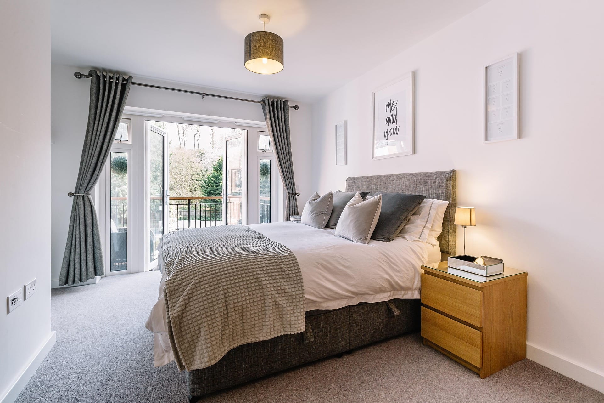 Chambre avec lit double, porte-fenêtre ouvrant sur un balcon et chevets en bois