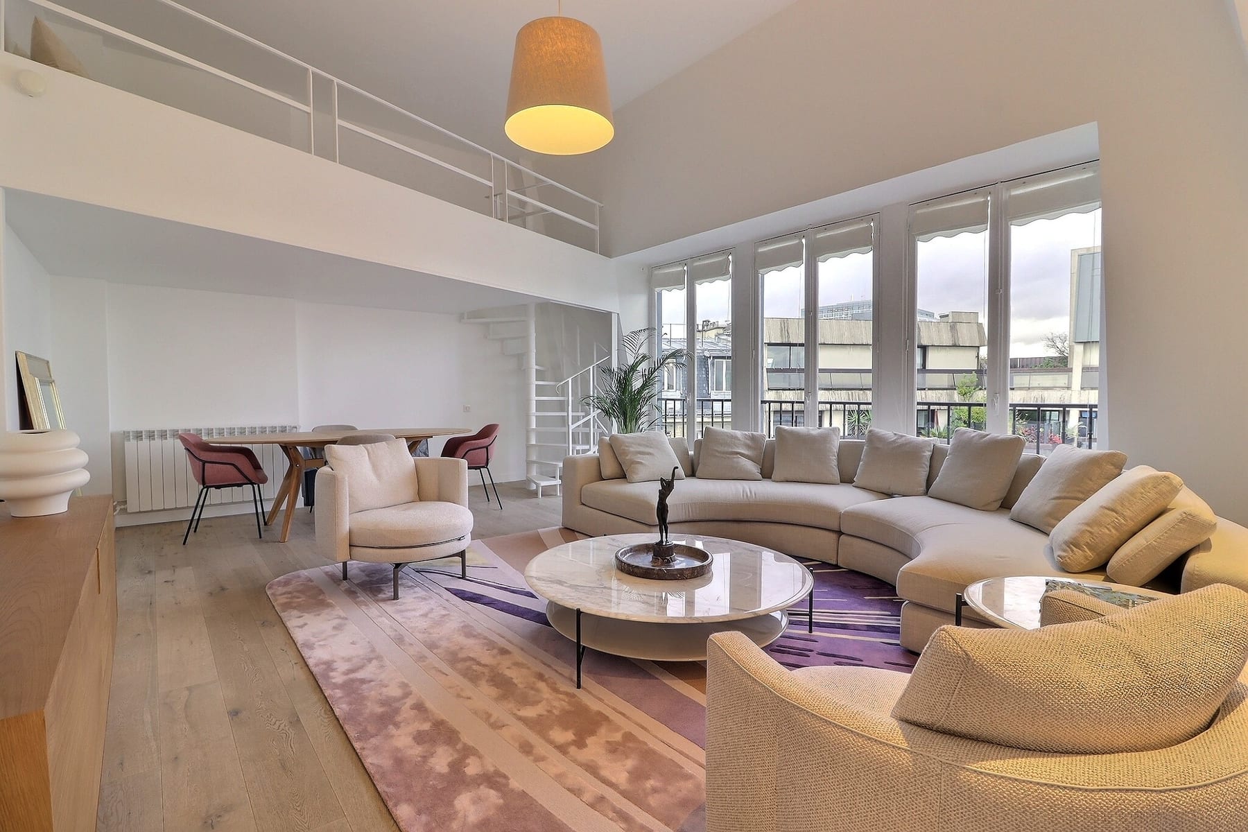 Séjour d’un duplex parisien avec mezzanine et grandes fenêtres sur les toits