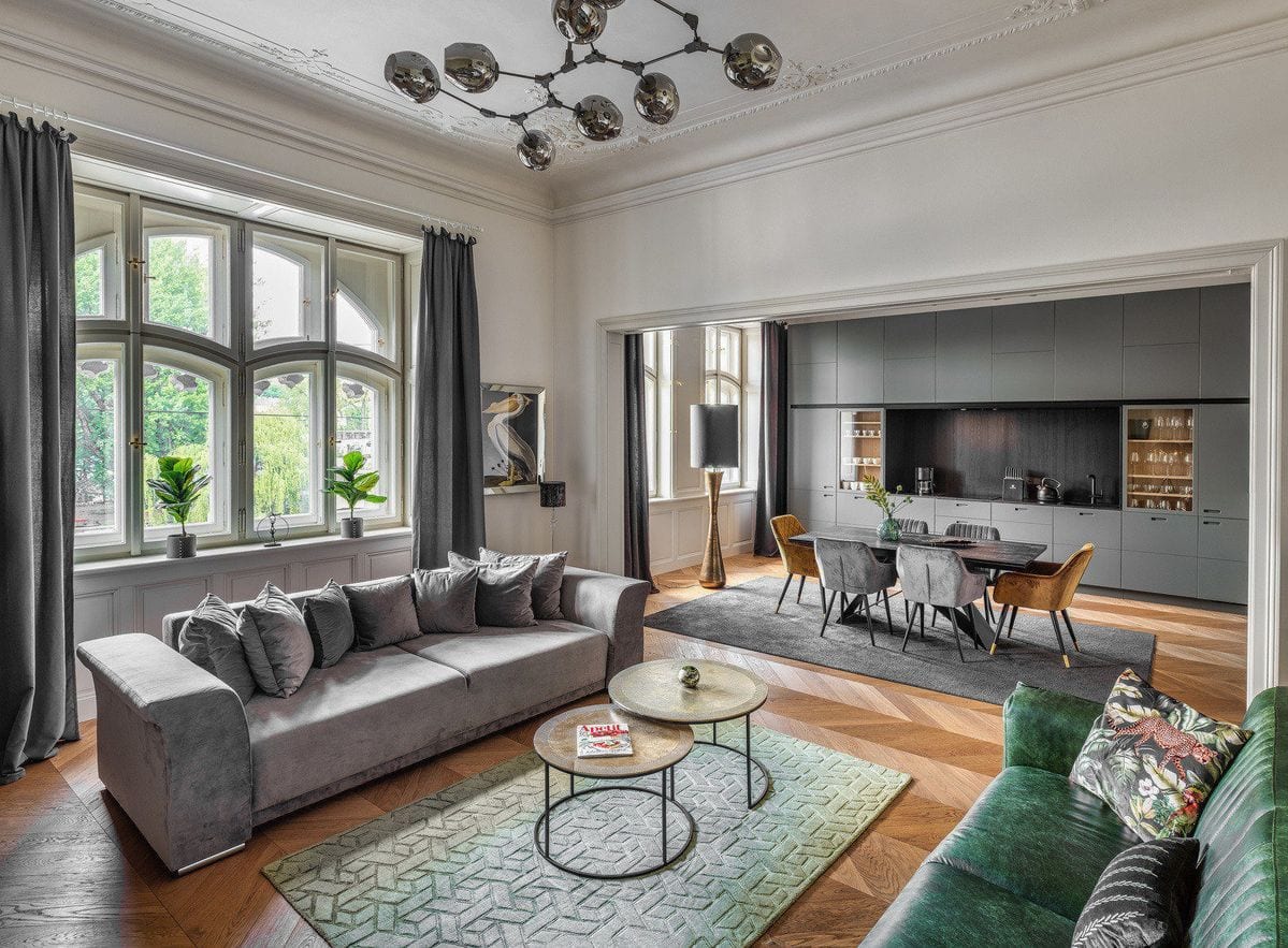 Grand séjour à moulures et lustre contemporain, ouvert sur une salle à manger et une cuisine sombre